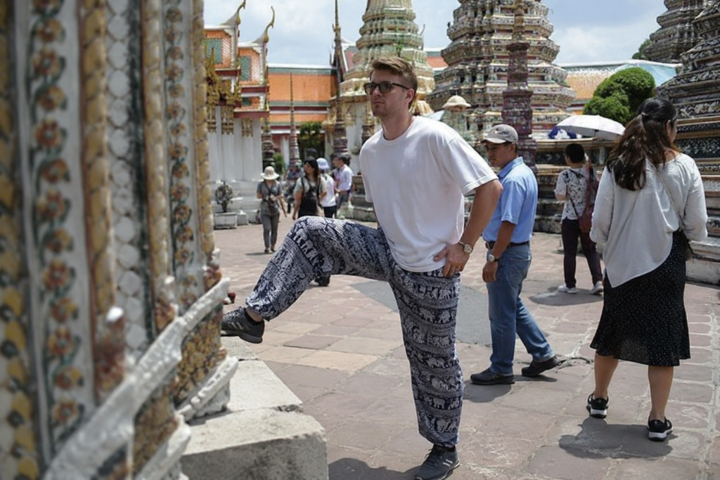 Tourist pointing his foot at a temple structure in Thailand, showing disrespectful behaviour in a sacred place