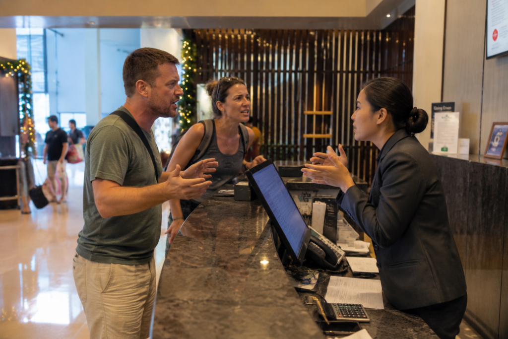 Tourists aggressively arguing with hotel reception staff in a hotel lobby in Thailand