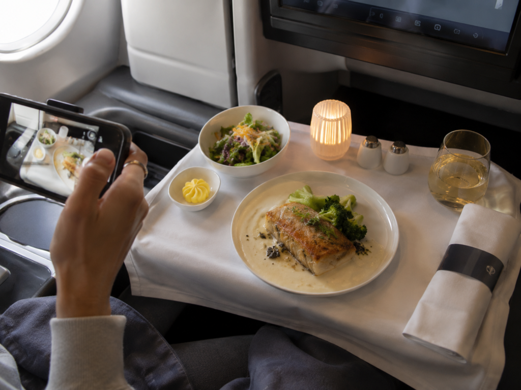 Luxury business class meal on an airplane while a passenger photographs the food during the flight