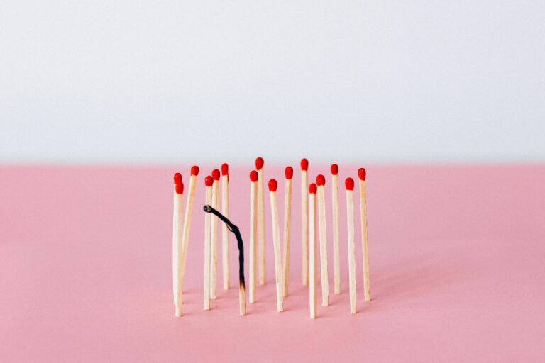 Burned matchstick standing among normal matches symbolising emotional exhaustion and job burnout