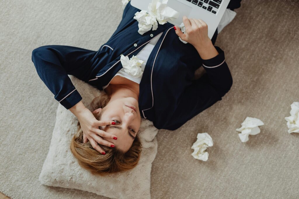 Exhausted woman lying on the floor with a laptop during severe work burnout and emotional exhaustion