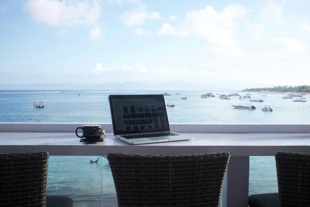 Laptop and coffee on a seaside balcony representing the digital nomad remote work lifestyle