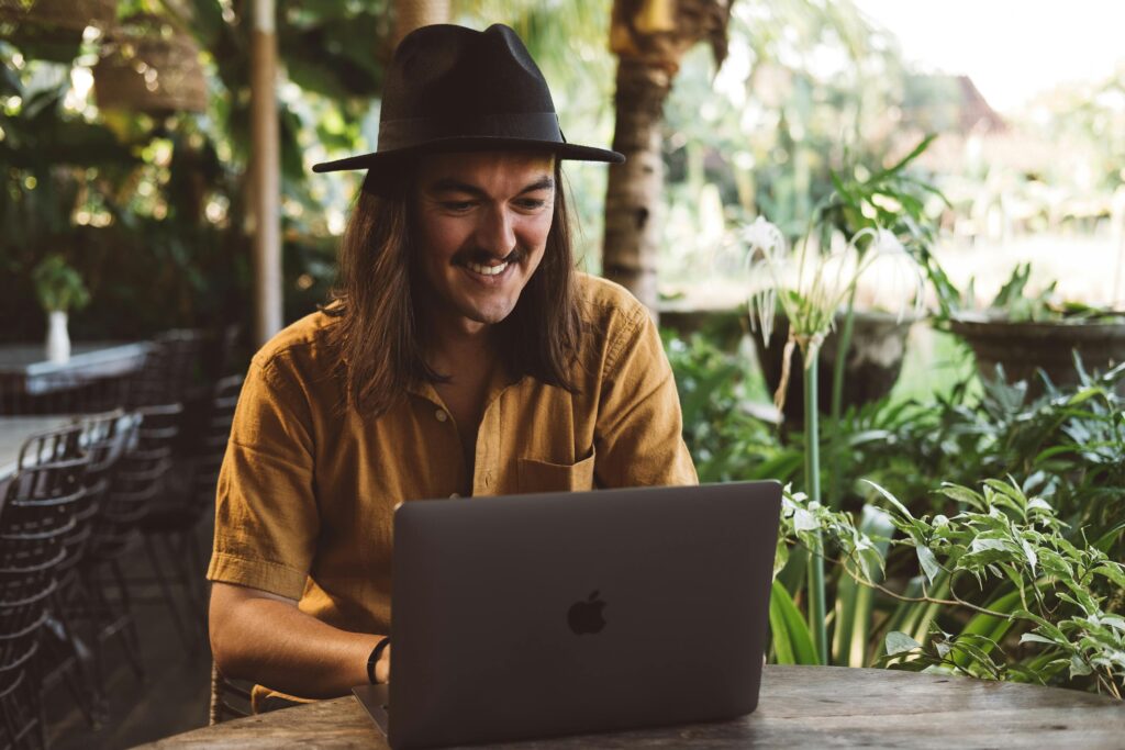 Digital nomad working remotely on a laptop in a tropical outdoor café