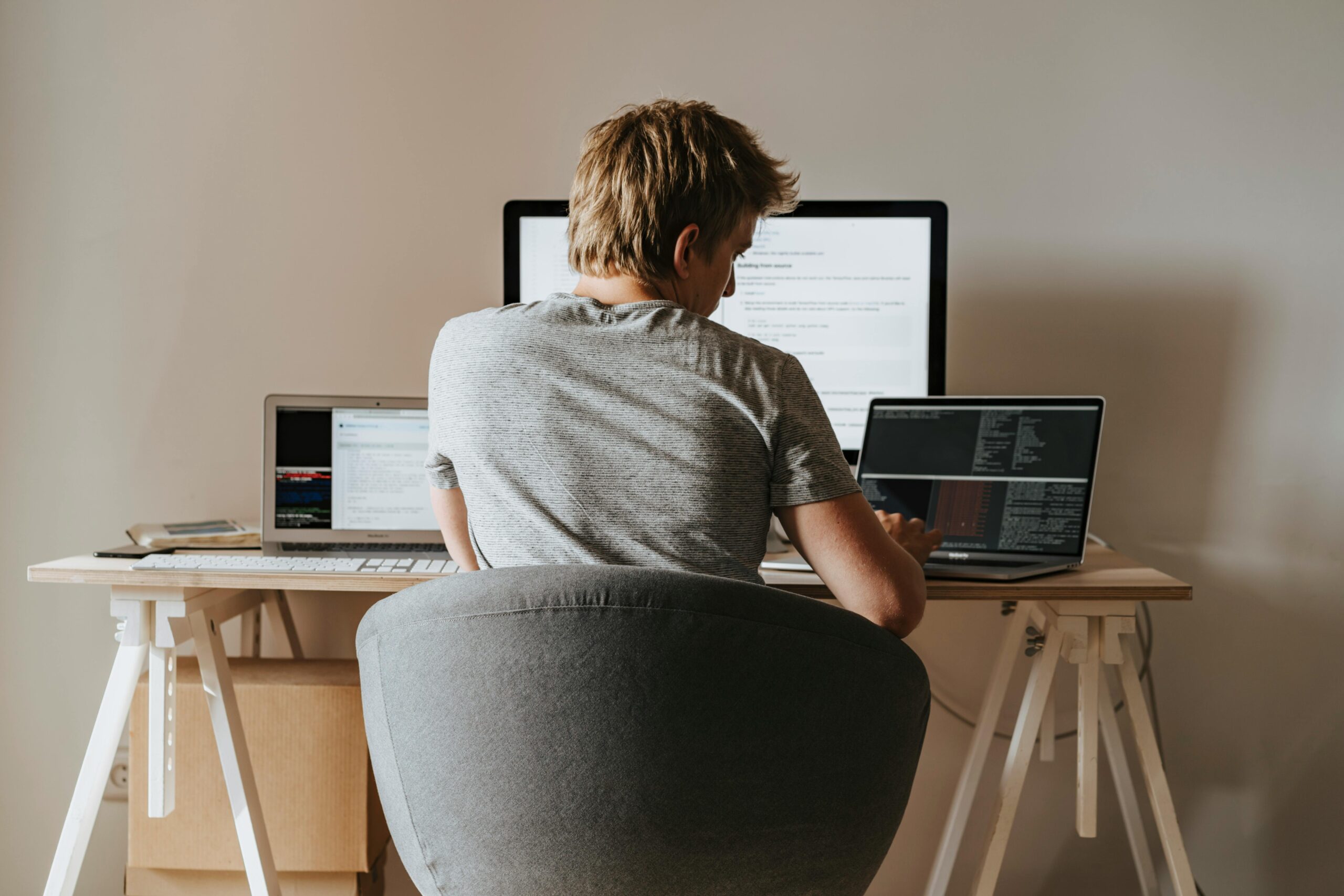 Person working alone from home at a desk with multiple screens, representing remote work loneliness and emotional isolation