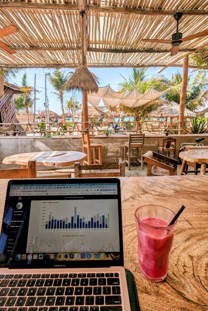 Laptop on a table at a tropical beach cafe representing remote work and digital nomad lifestyle