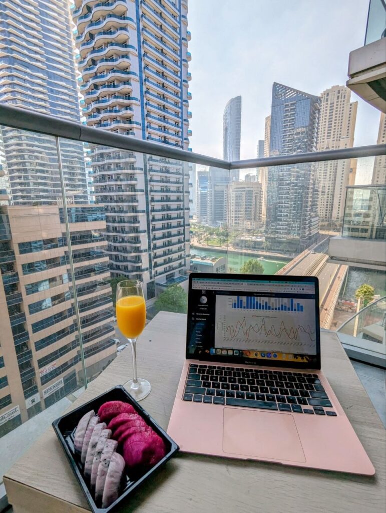 Remote work setup with laptop and breakfast overlooking Dubai Marina skyline