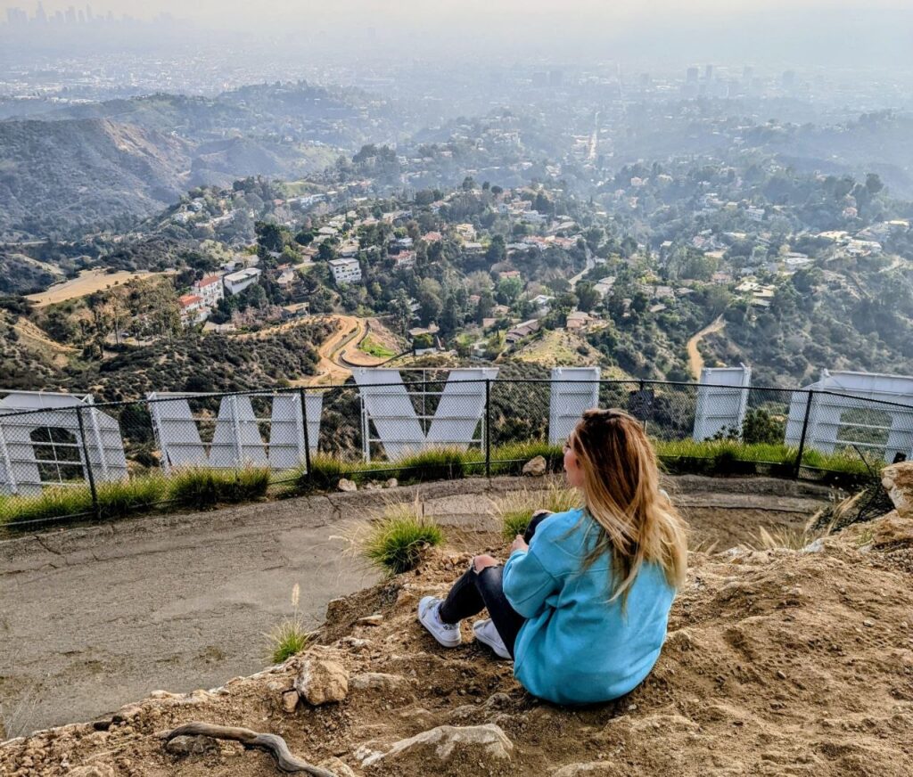 Woman sitting above the Hollywood Hills in Los Angeles overlooking the city skyline
