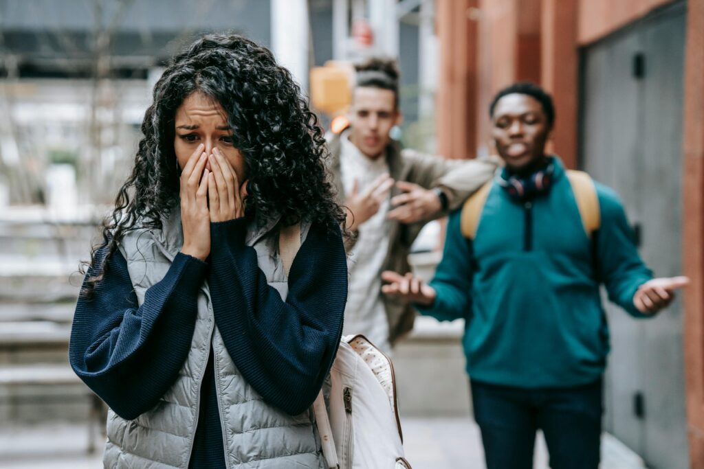 Emotional scene showing a woman feeling isolated and distressed while people behind her appear confrontational, illustrating the emotional damage of toxic friendship