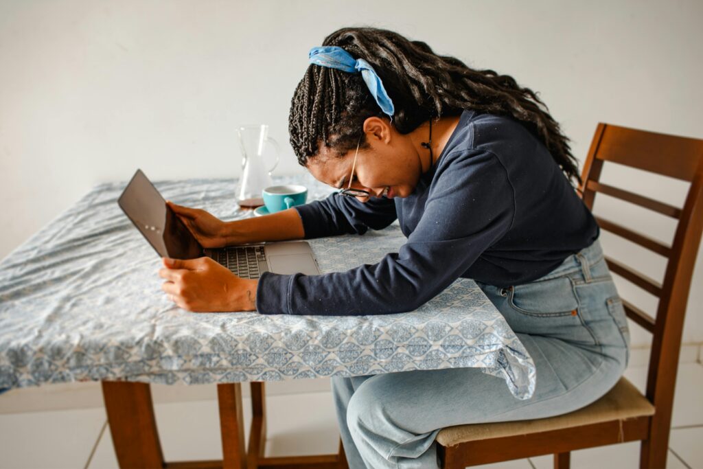 Exhausted woman sitting at a table with a laptop during severe work burnout and emotional stress