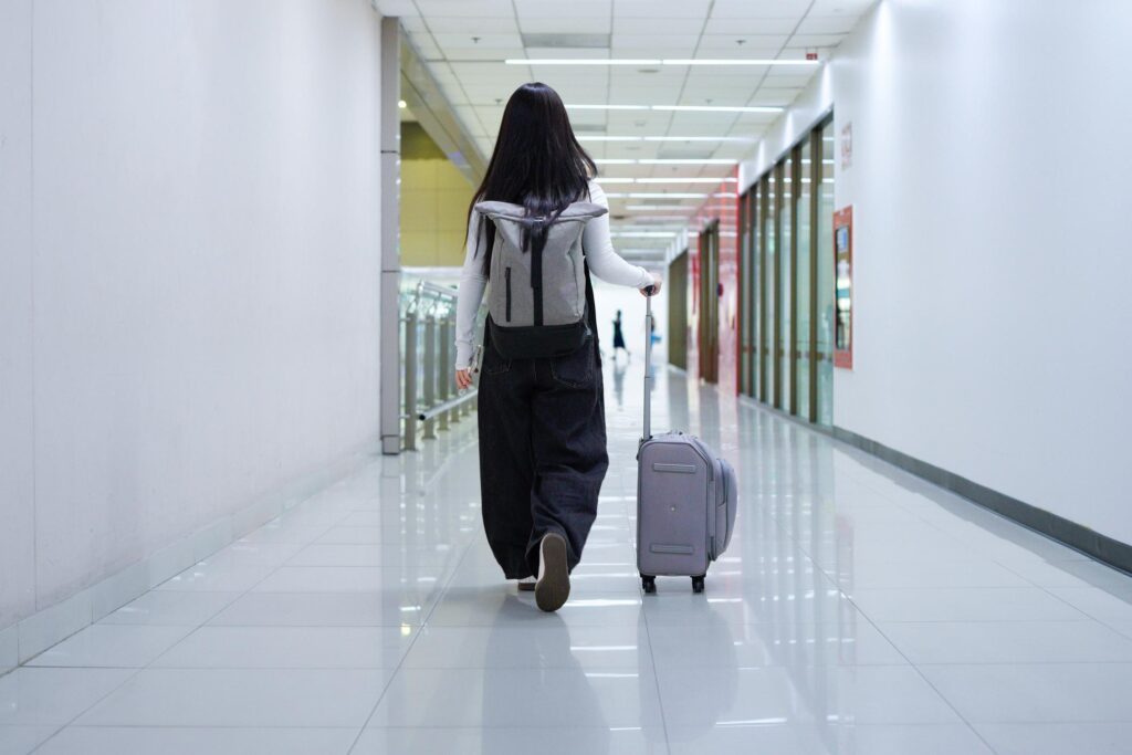 Digital nomad walking through airport terminal with suitcase and backpack