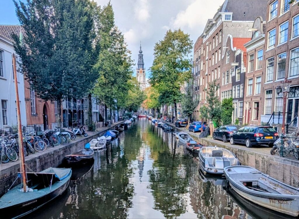 Amsterdam canal-lined residential neighborhood with historic houses, bicycles, boats, and everyday city life.