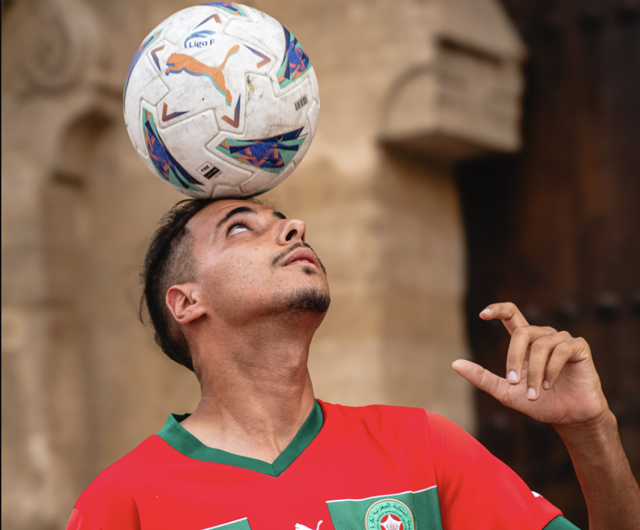 Young Moroccan football player balancing a football while wearing the Morocco national team jersey