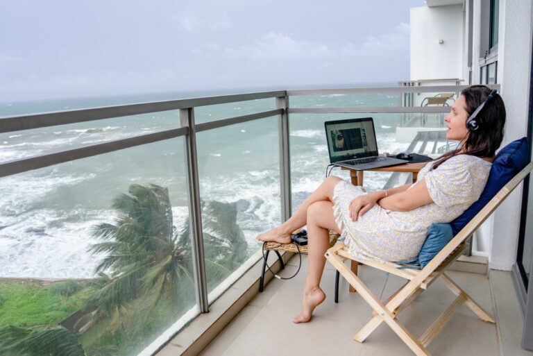 Digital nomad working remotely from an oceanfront balcony, representing affordable alternatives to Dubai for remote workers.