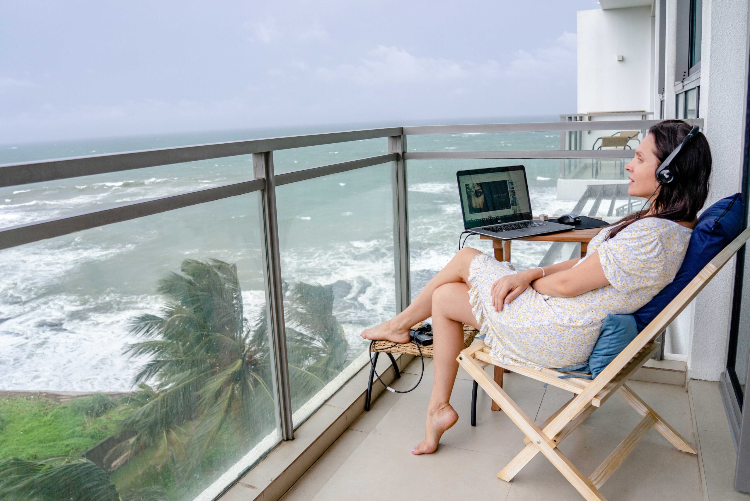 Digital nomad working remotely from an oceanfront balcony, representing affordable alternatives to Dubai for remote workers.