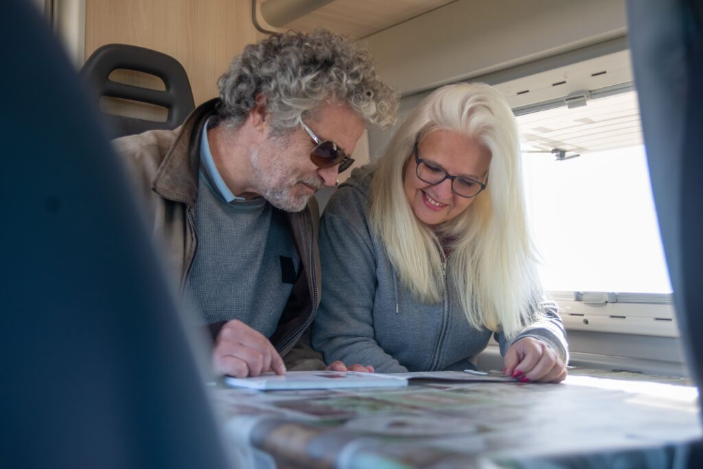 Retired couple planning a road trip inside a campervan, representing the Grey Nomad lifestyle in Australia.