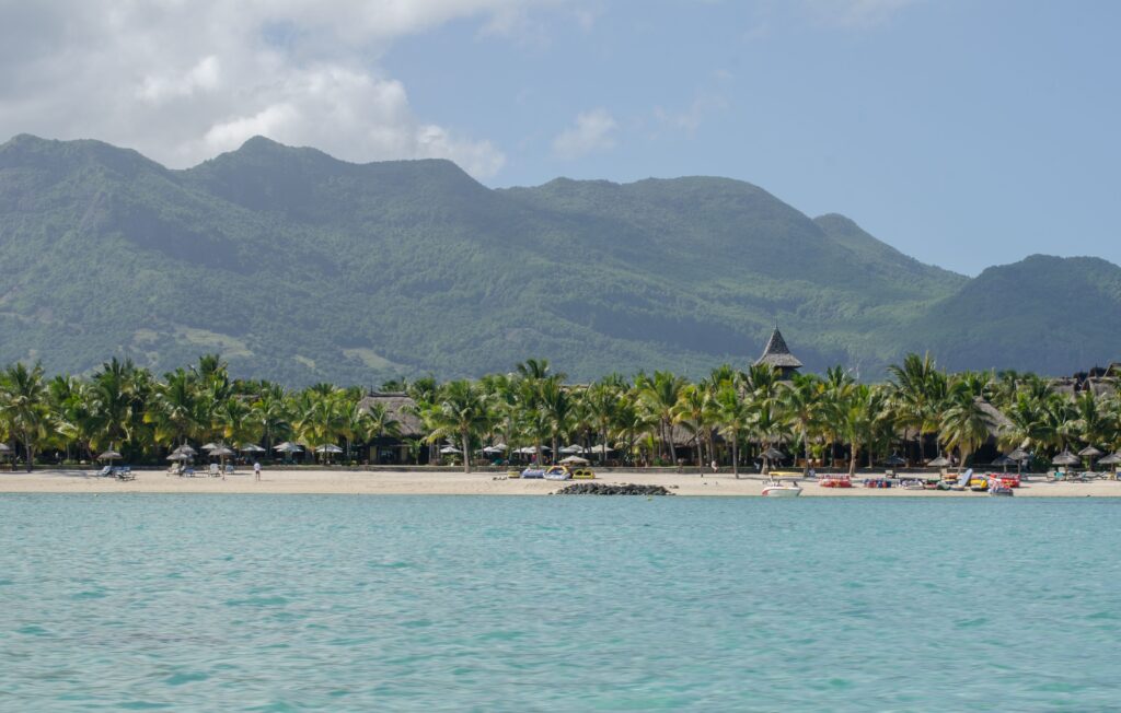 Tropical beach in Mauritius with turquoise water and lush mountains, a peaceful island destination for digital nomads and remote workers.