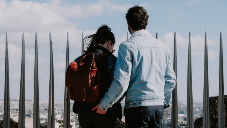 Couple standing together overlooking a city during a trip, representing a travel romance and the emotional connections formed while travelling.