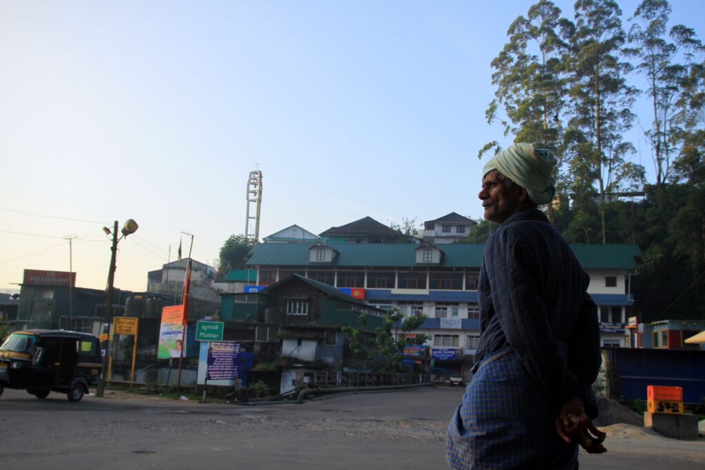 Street scene in Munnar, Kerala, India with a local resident and hillside town in the background