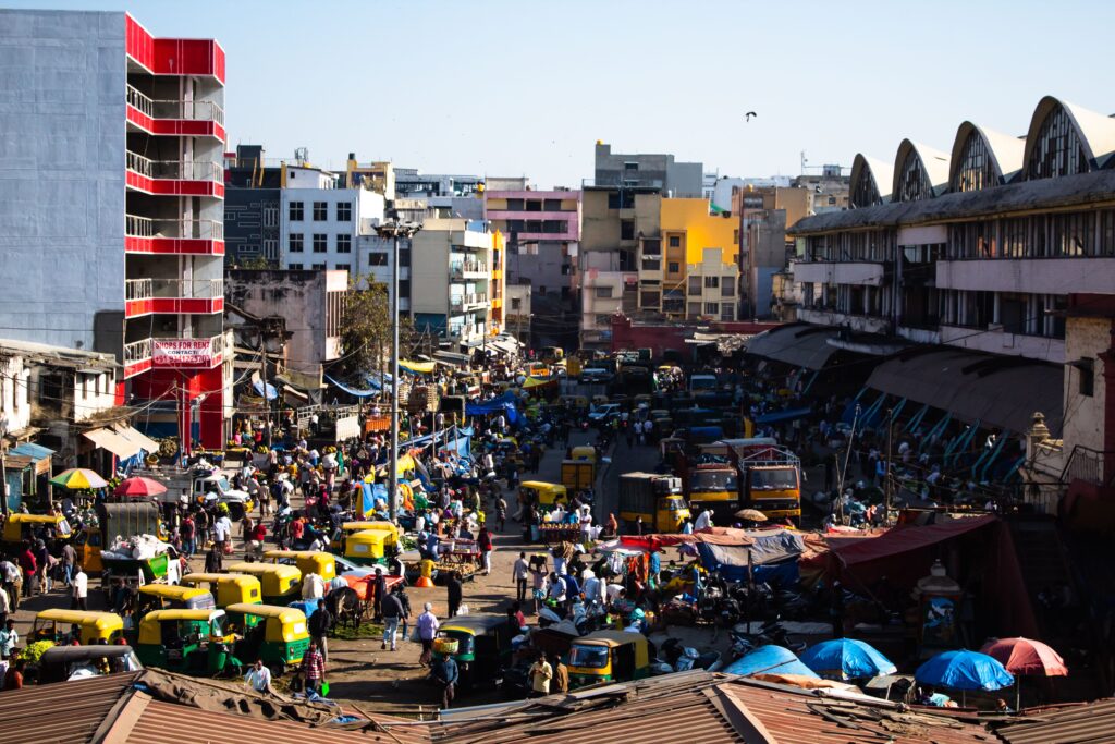 Busy street and market area in Bangalore, India with traffic, auto-rickshaws and commercial buildings