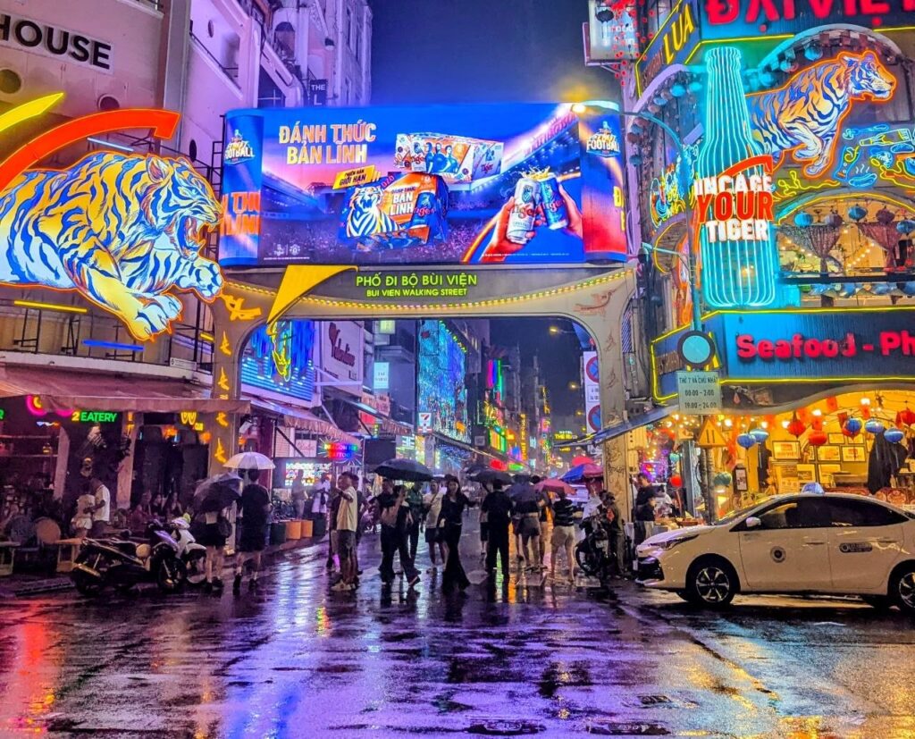 Bùi Viện Walking Street in Ho Chi Minh City at night, illuminated by colorful neon signs with restaurants, bars, and crowds of locals and international visitors.