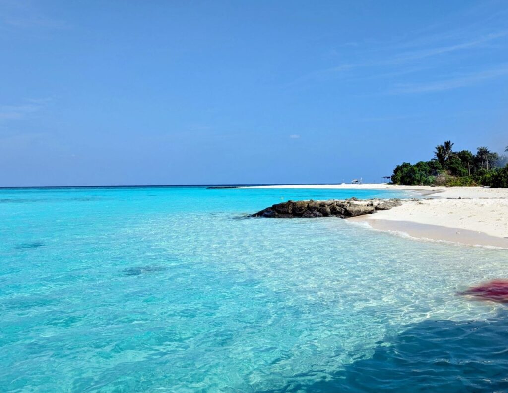 White sand beach and crystal-clear turquoise water on a local island in the Maldives.