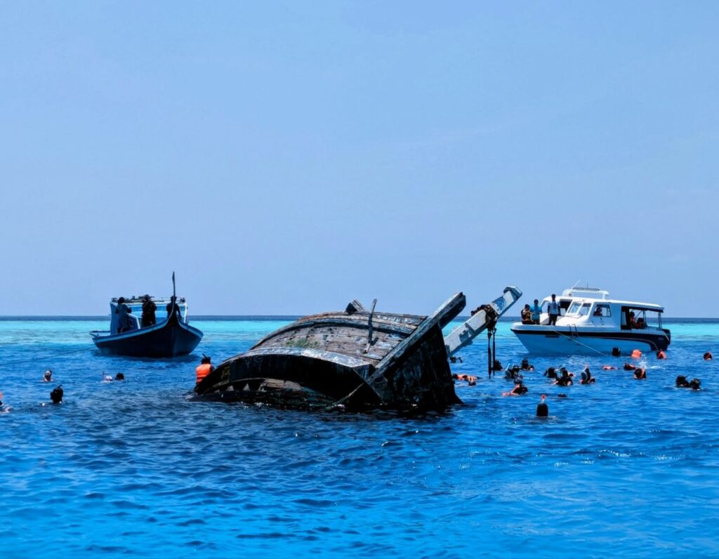 Snorkelers exploring a shipwreck during a boat excursion in the Maldives near Maafushi Island.