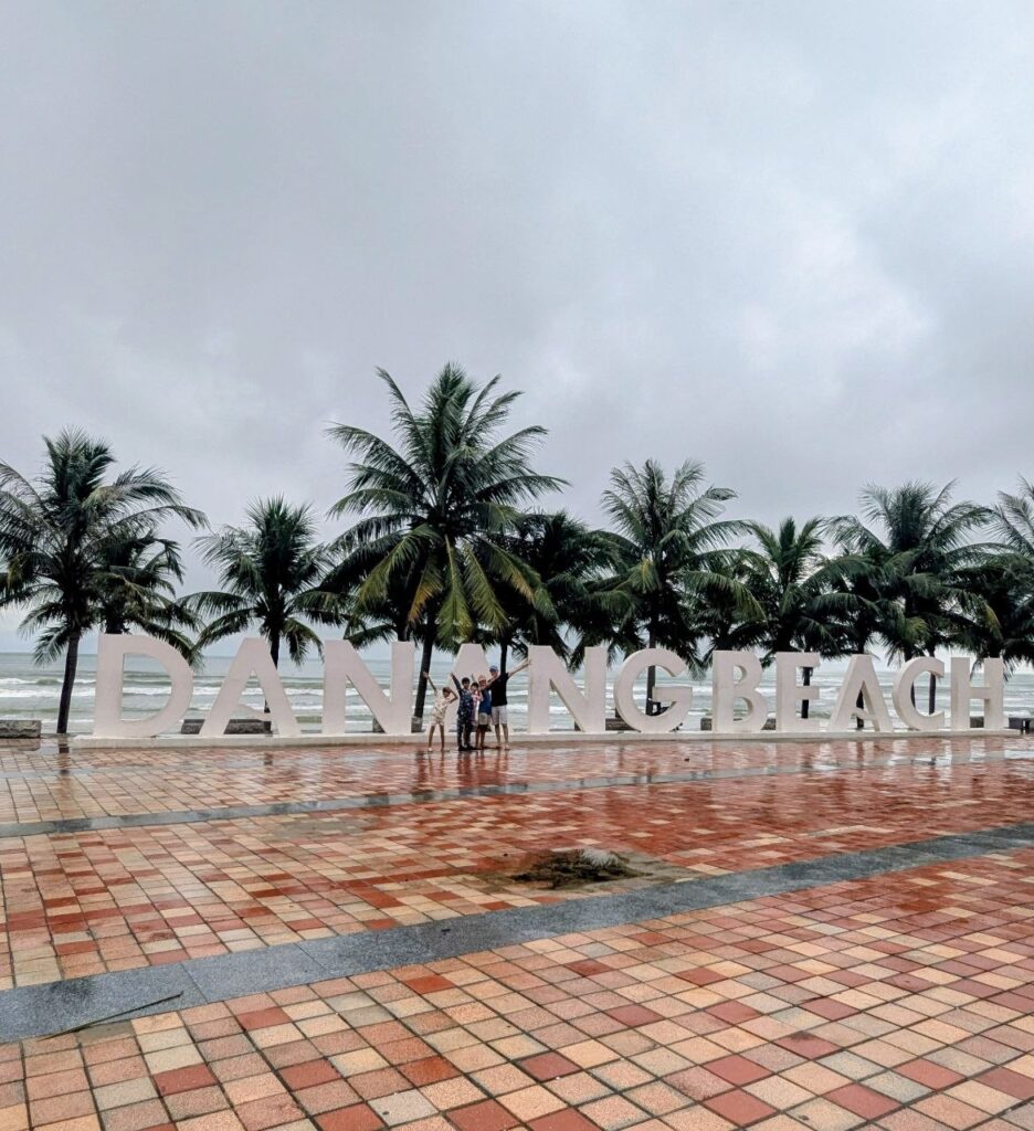 Da Nang Beach during rainy weather in September, with wet pavement, palm trees and grey skies