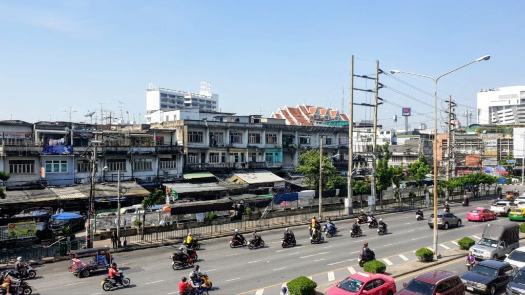 Street view of a residential neighborhood in Bangkok showing local apartment buildings, traffic and everyday city life