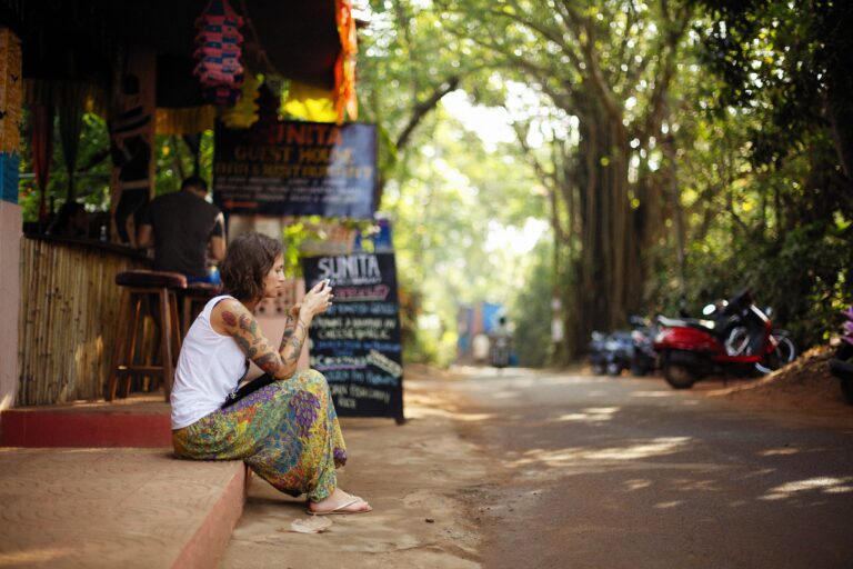 Digital nomad sitting outside a café in Goa, India, using a smartphone.