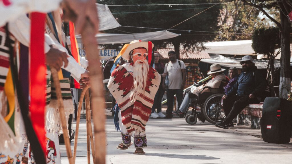 Traditional Mexican performer wearing a colorful costume at an outdoor cultural event in Mexico