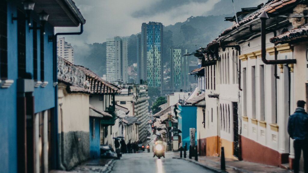 Historic street in Colombia with colorful colonial buildings and modern high-rise towers in the background