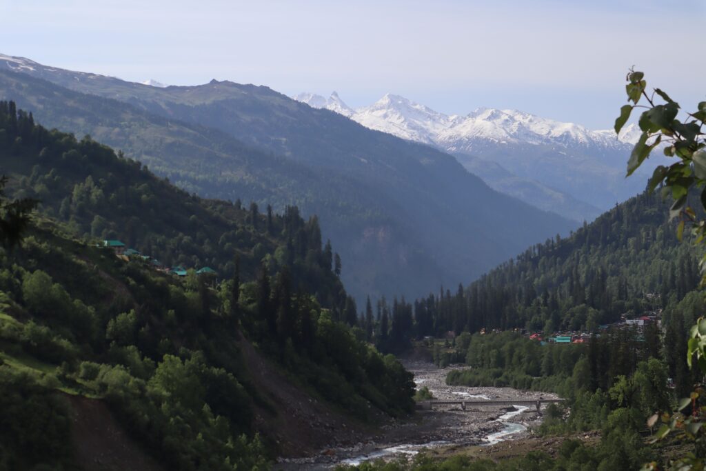 Mountain valley near Manali, Himachal Pradesh, India, surrounded by snow-capped Himalayan peaks.