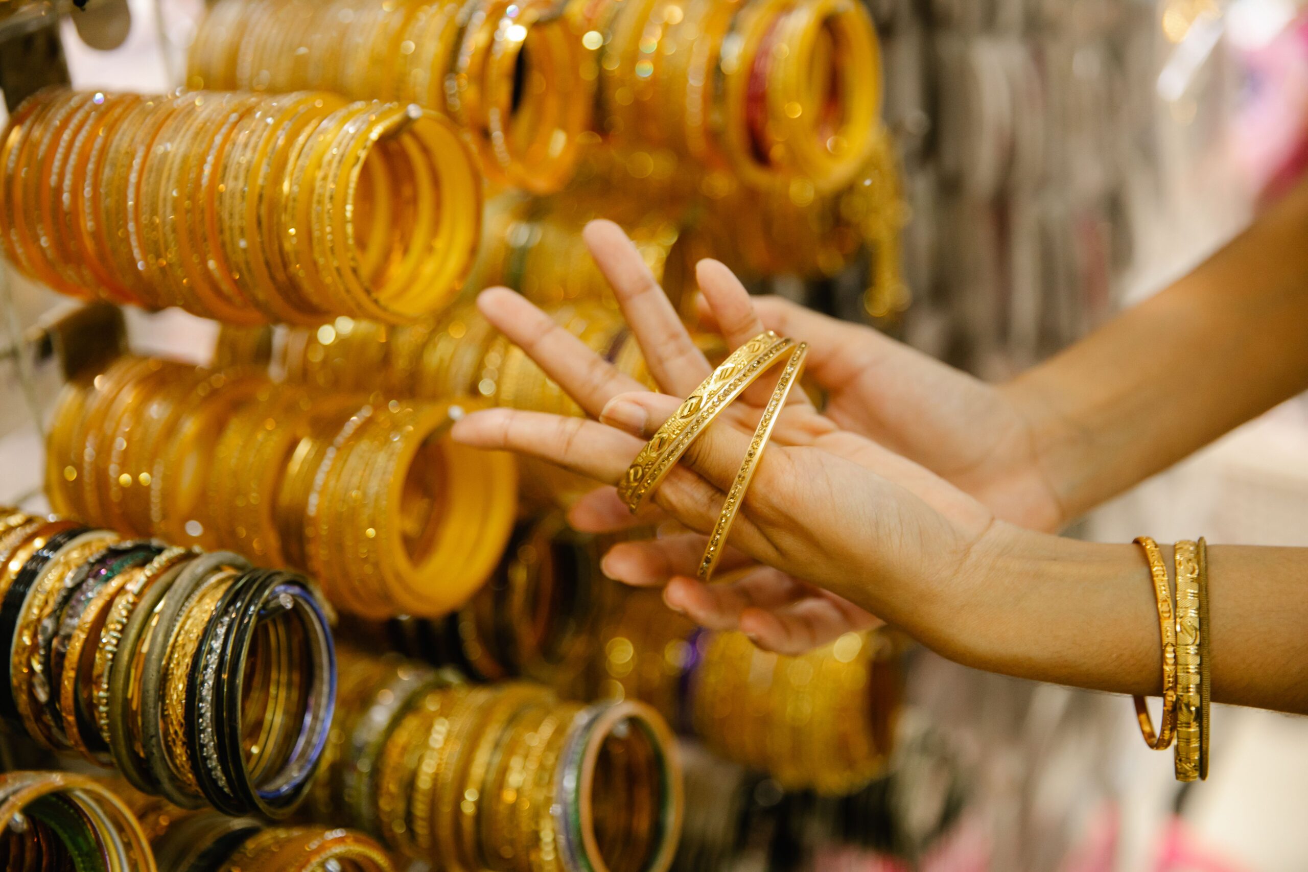 Woman trying on yellow gold bangles at a jewellery market