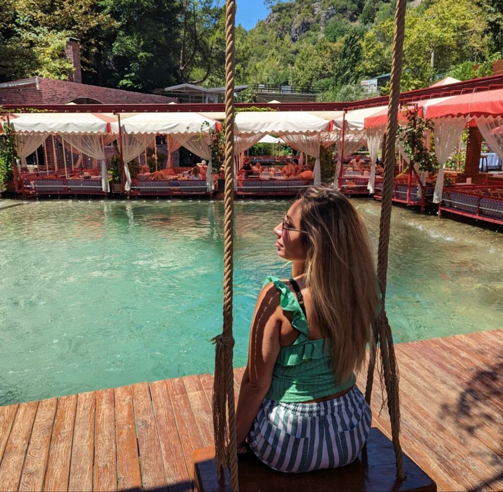 Sitting on a swing beside a turquoise spring in Turkey during my travels